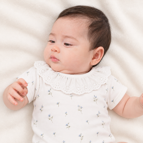 Bebé usando el body Bebé niña con body broderie floral estampado azul algodón Pima certificado – Rikury