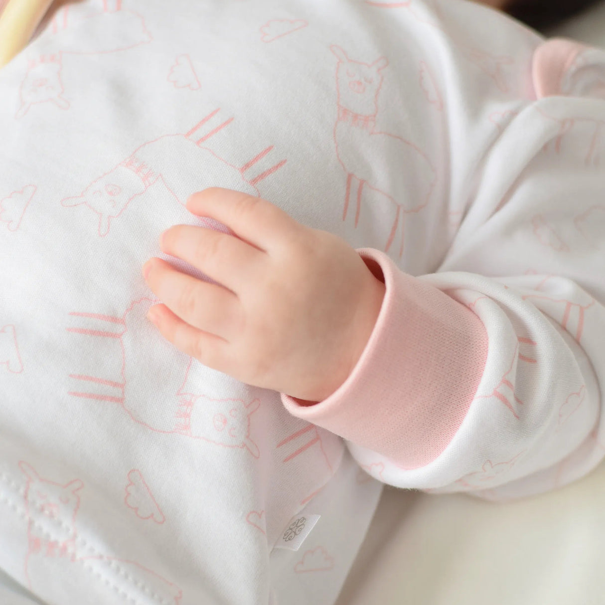  "Detalle de polo pijama llamita rosa de algodón pima para bebé"