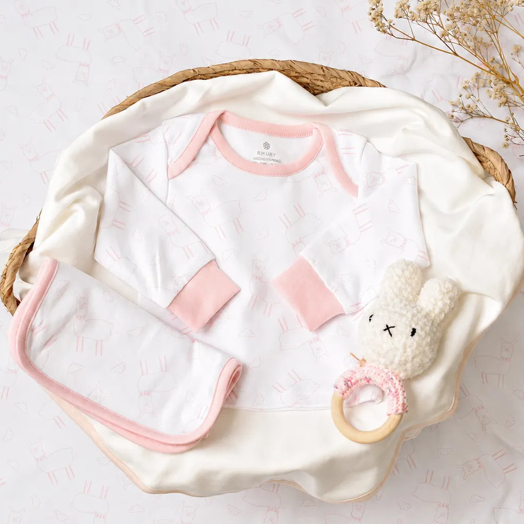 "Pijama llamita rosa de algodón pima para bebé doblada en canasta"